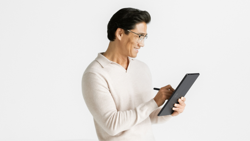 Mężczyzna siedzący i trzymający urządzenie Surface Pro 10 w trybie tabletu