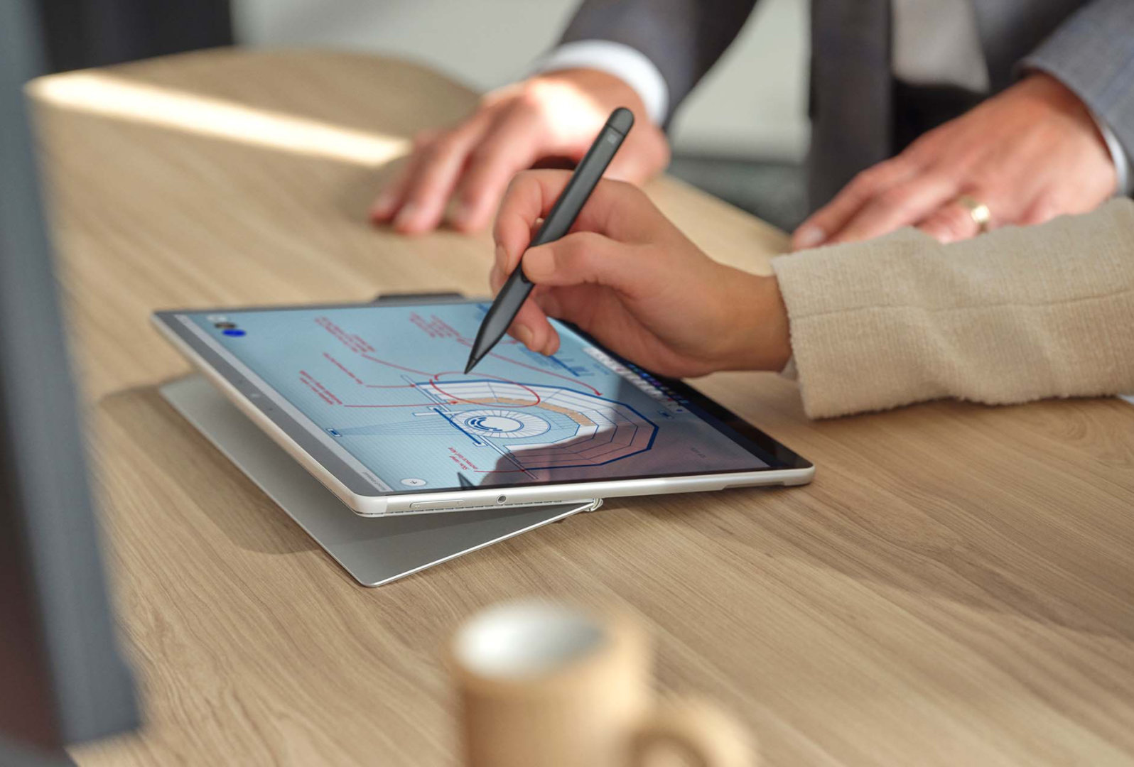 A person's hand is observed using Surface Slim Pen 2 on the screen of Surface Pro 8