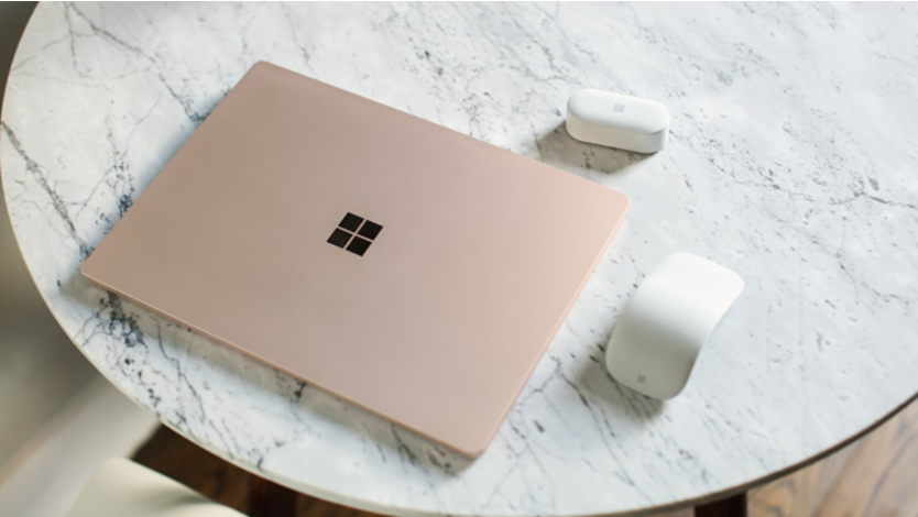Surface laptop on a table with Surface Arc Mouse and Surface Earbuds