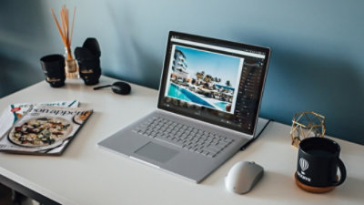 Laptop sitting on a desk with a mouse and coffee cup sitting nearby