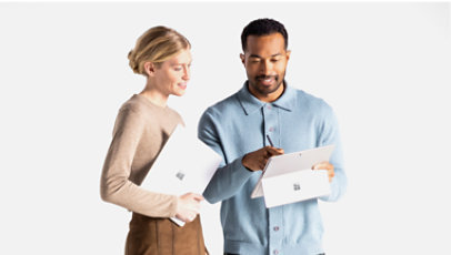 Two people standing next to each other holding Surface devices