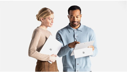 Two people standing next to each other holding Surface devices