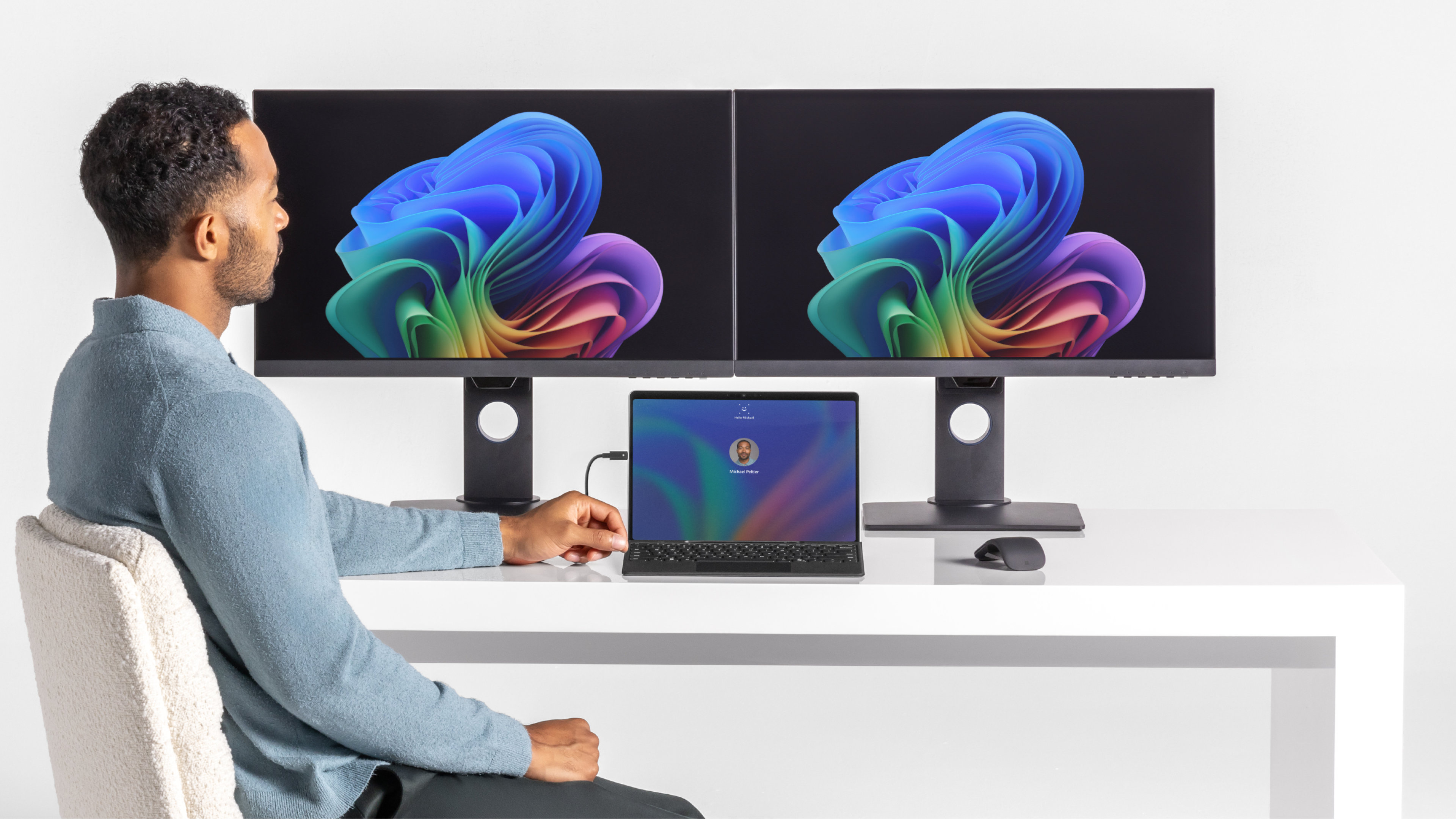 A man sitting at his desk with multiple displays