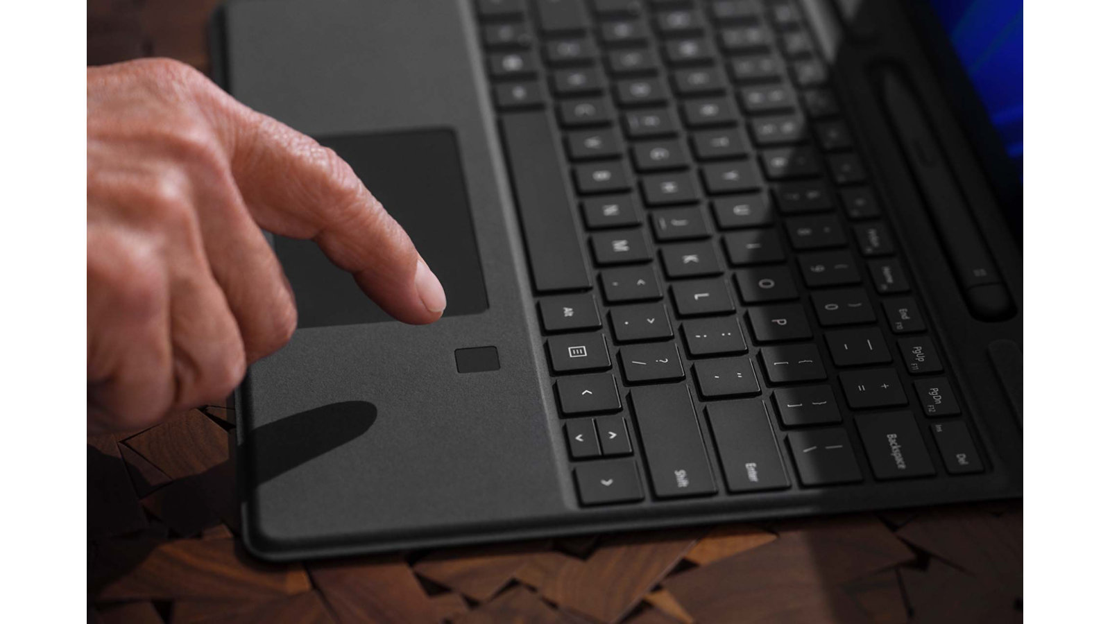 A person's finger hovers over the biometric sign-in feature on Surface Pro Signature Keyboard