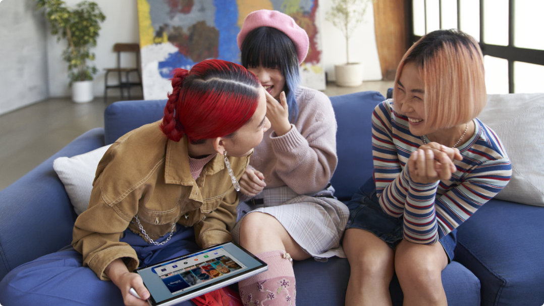 Three young women with a device laughing with each other
