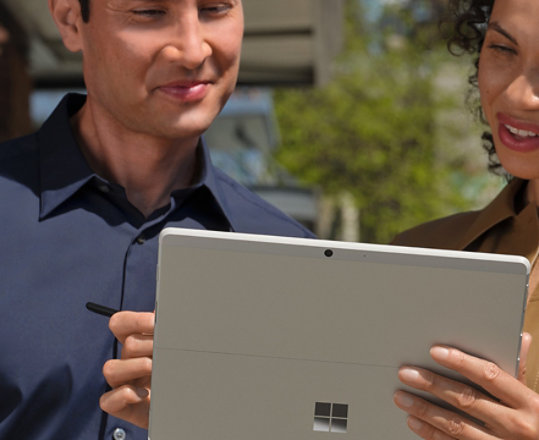 Dwie osoby w wielkomiejskim biurze współpracujące na urządzeniu Surface Go 3