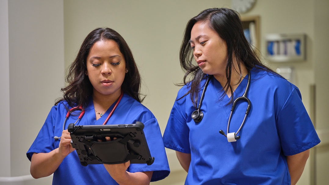 Two nurses collaborate while using a Surface device in a medical setting