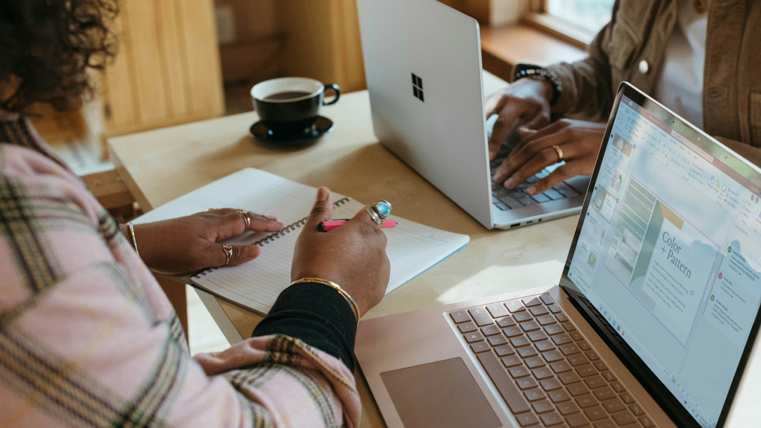 Two people at a desk using Surface devices