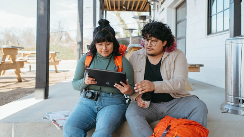 Two people using a Surface Pro 2-in-1 PC while sitting on a stoop