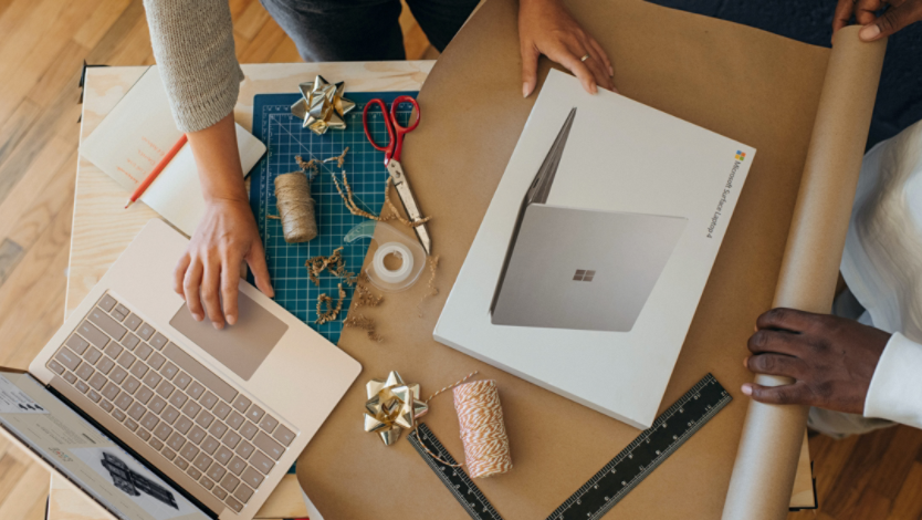 Two people wrapping a Surface laptop