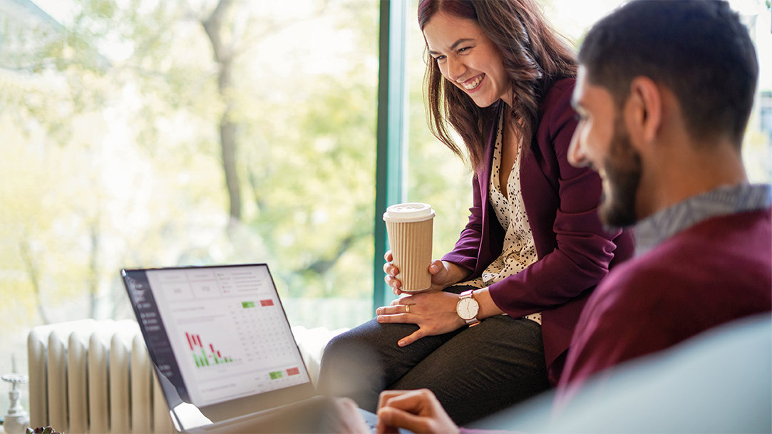Two smiling coworkers looking at productivity apps on a Windows computer