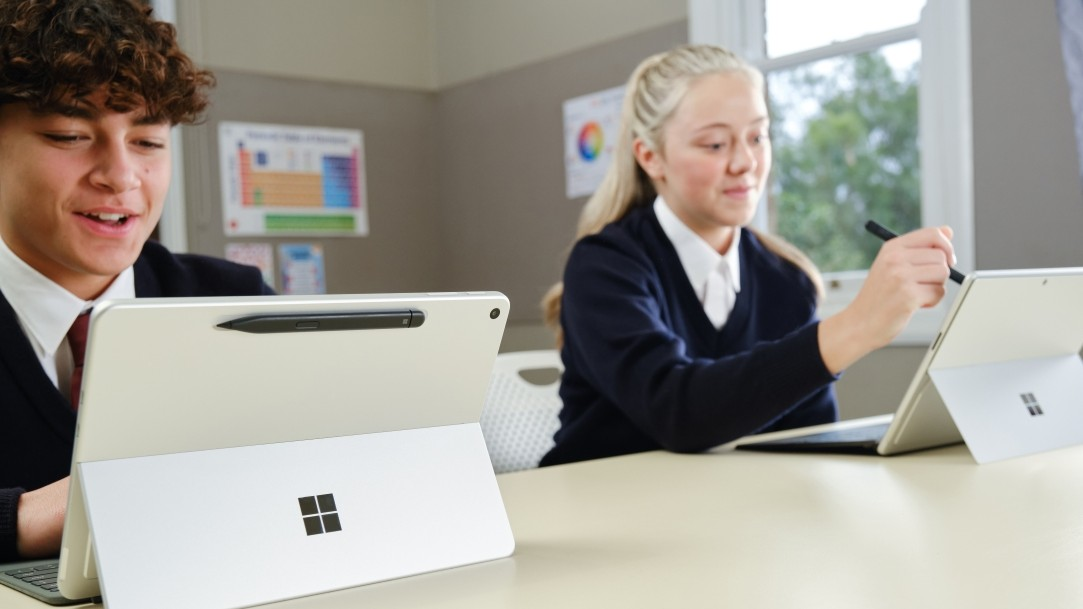 Two students in a classroom using Surface Pro 2-in-1s and a Surface Slim Pen accessory