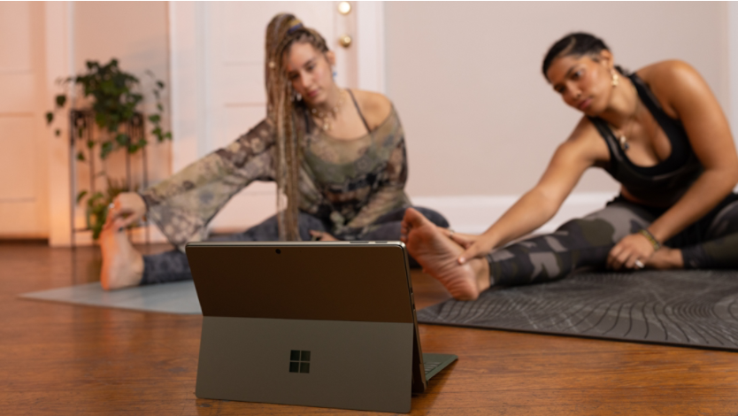  Two women doing yoga in front of a Surface