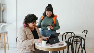 Two women laughing as one types on a Surface keyboard