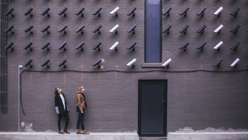 Two women looking up at a wall with many security cameras