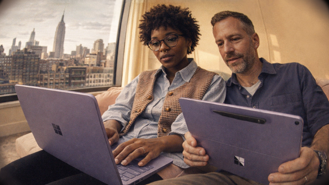 View through a fisheye camera lens, a couple using a Surface Laptop and a Surface Pro 2-in-1 tablet / Slim Pen, comparing and evaluating their performance
