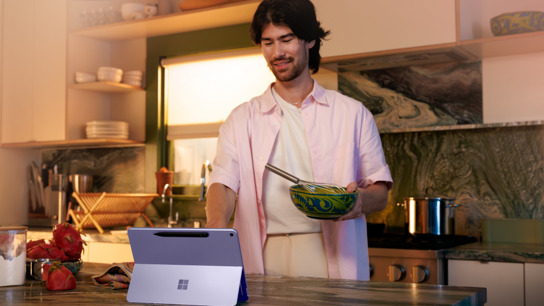 A man in the kitchen in the middle of cooking with a Surface Pro 2-in-1 laptop on the kitchen counter