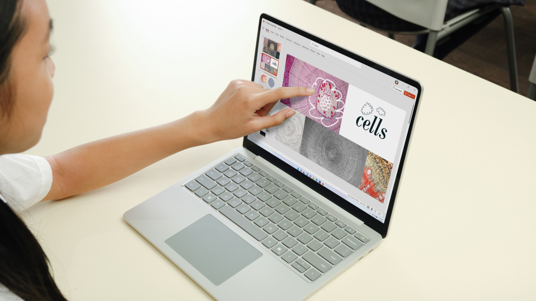 A side view of a young woman touching a Surface computer screen while her coworkers are in the background