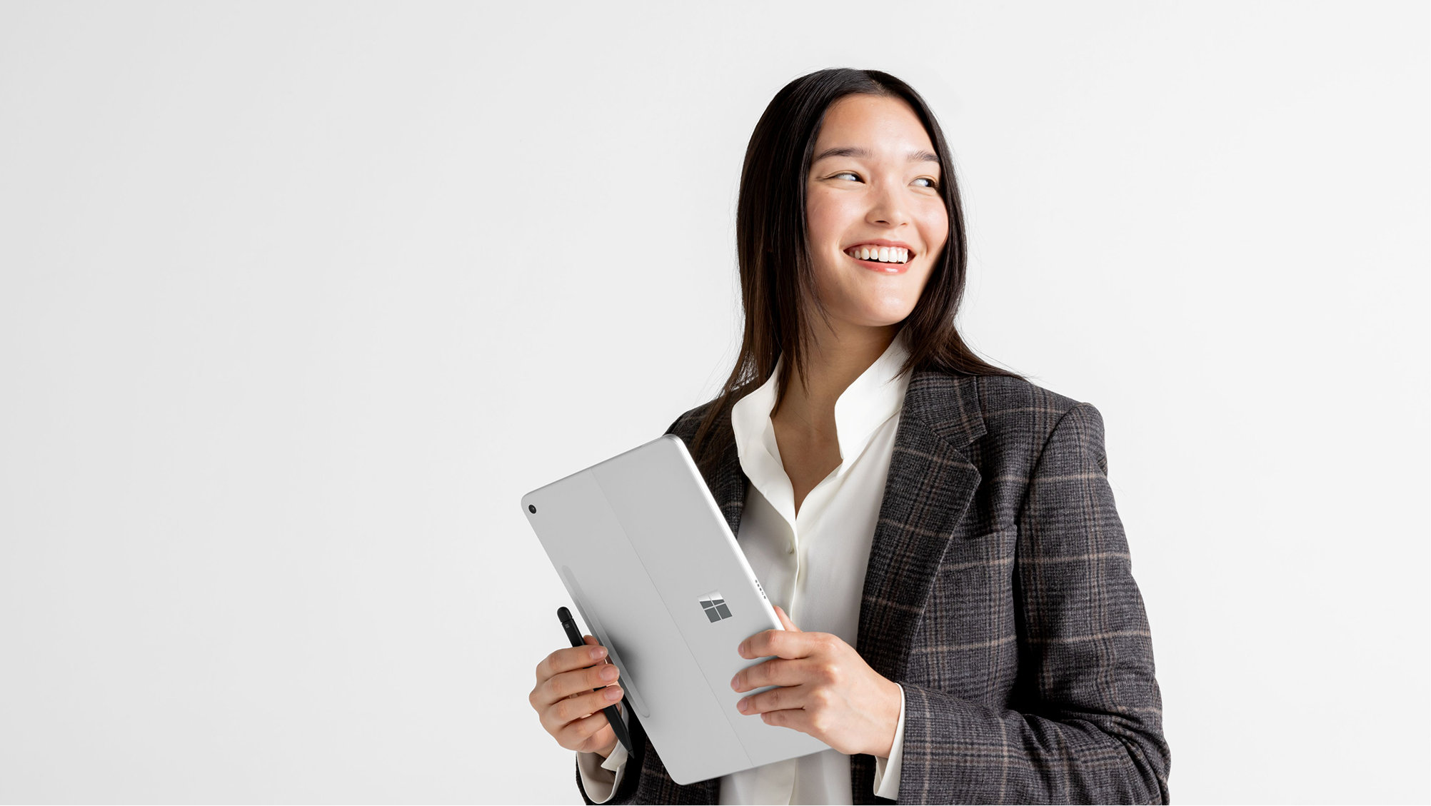 Smiling person holding a Windows Surface device and stylus