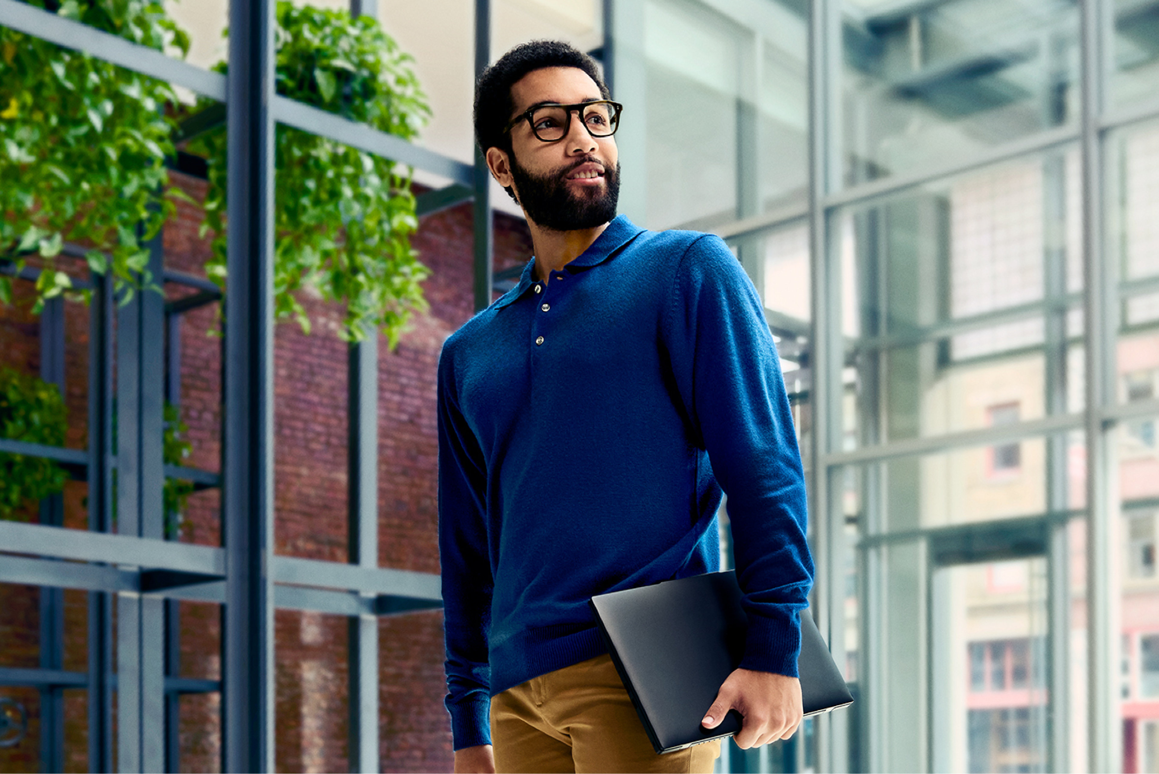 A person walking with a laptop in a brightly lit office space