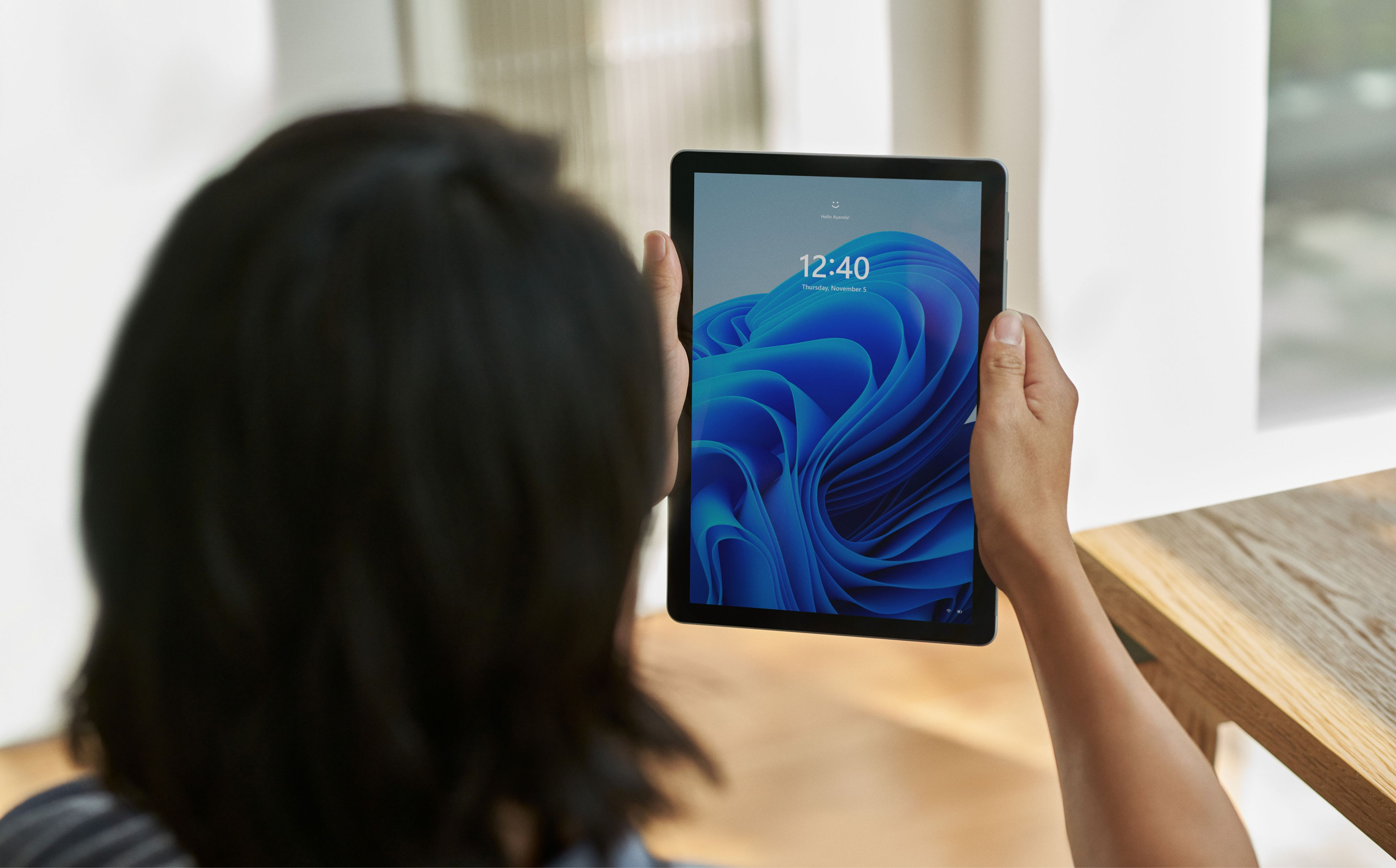 Person holding a tablet with a Windows bloom screen
