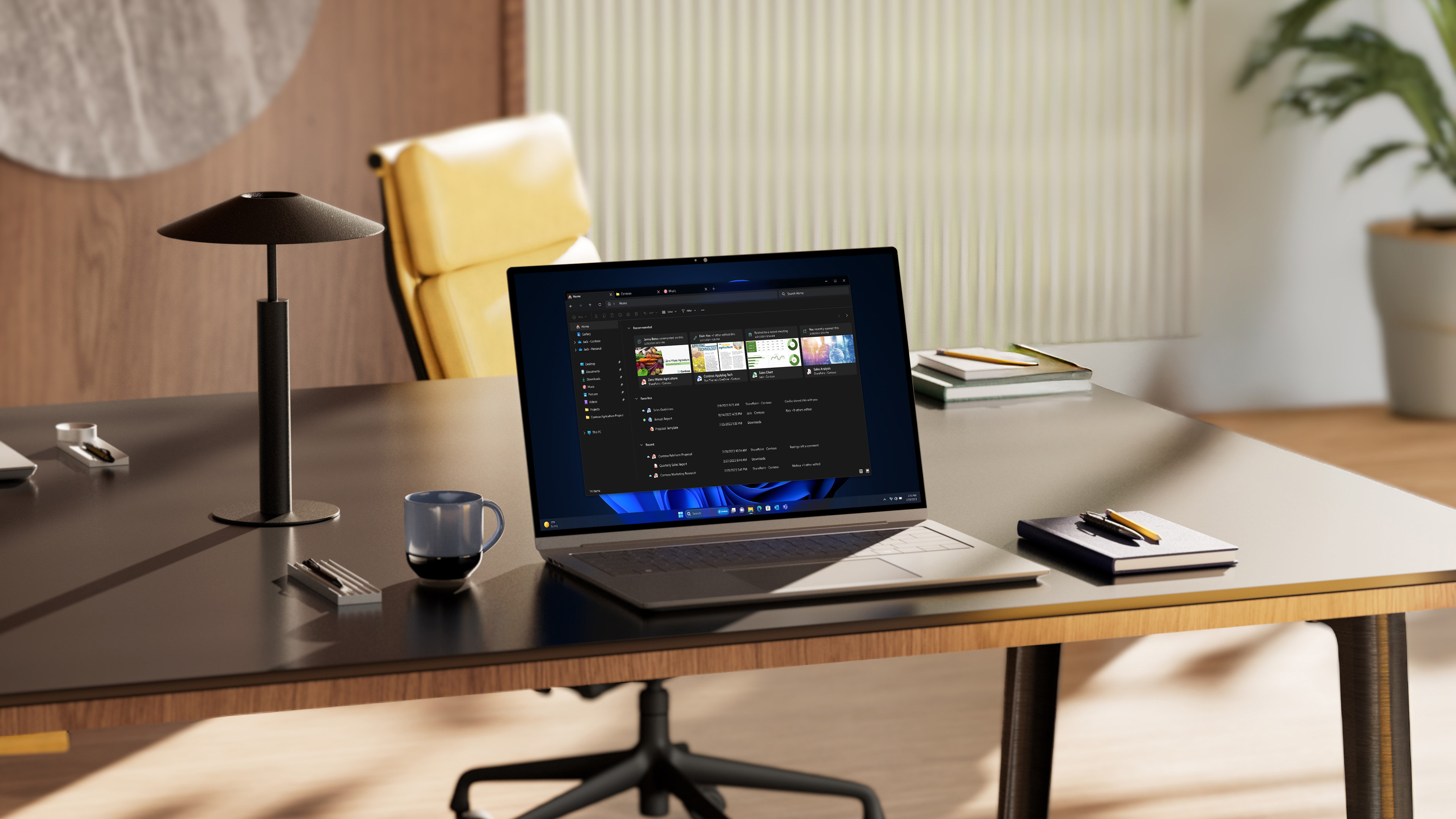 An open laptop displaying File Explorer in Windows, with tabs and AI powered recommendations in dark mode, sits on an office desk alongside notebooks and a coffee mug