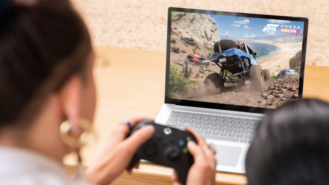 Woman games with a controller on Surface Laptop 5