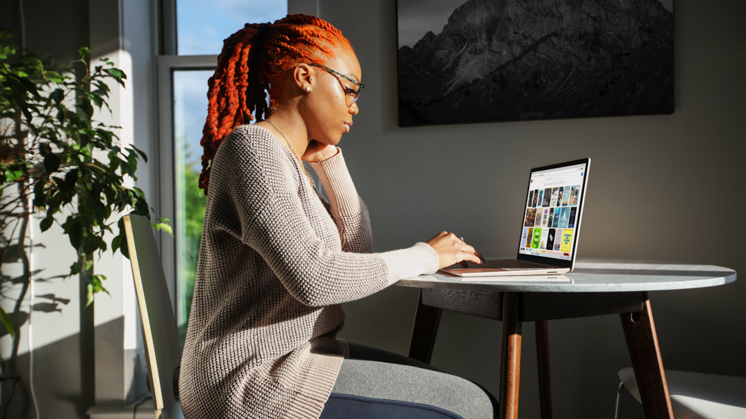 Woman in gray sweater using Surface laptop