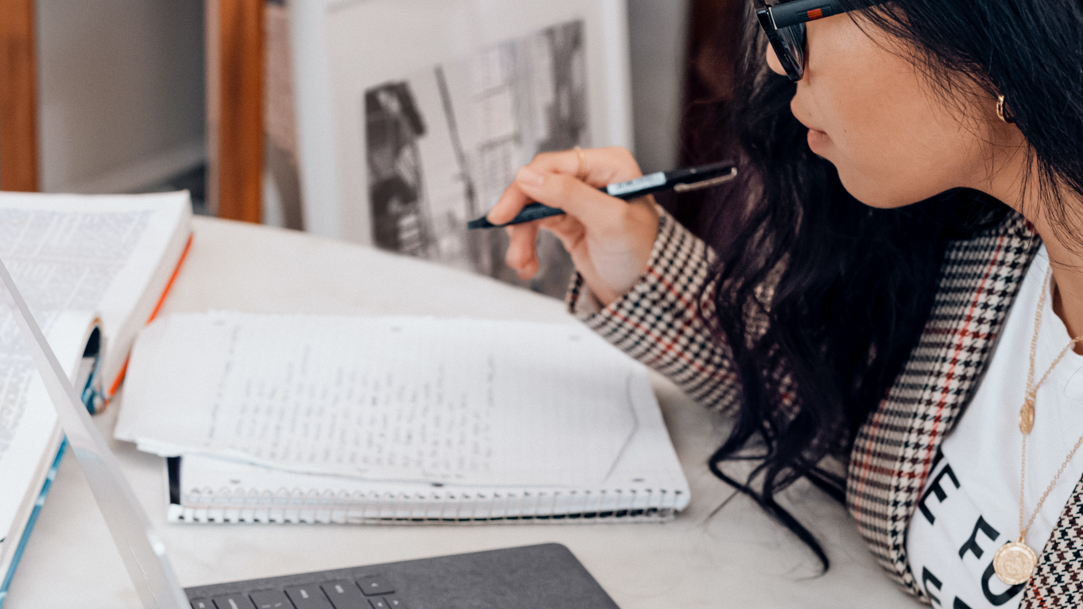 Woman in white and black plaid long sleeve blazer using a Microsoft Surface laptop