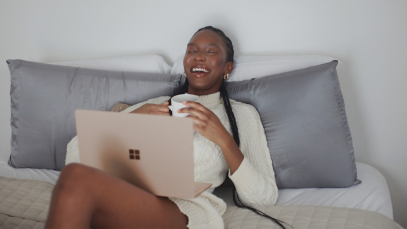 Woman laughing in bed with Surface device