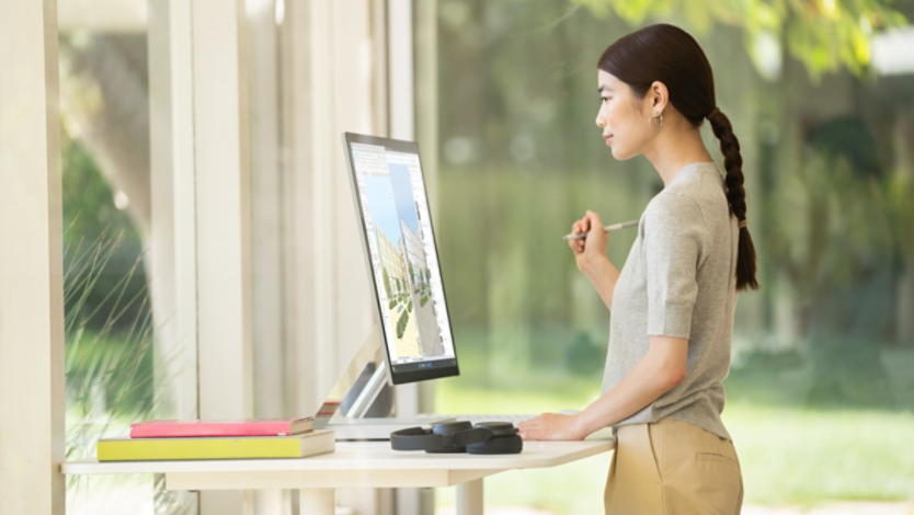 Woman looks at desktop computer at a standing desk