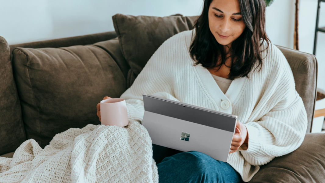 Woman reading on Surface Pro 9 on a couch