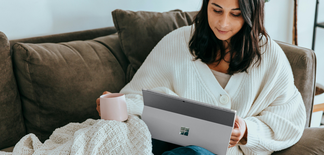 Woman reading on Surface Pro 9 on a couch