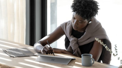 A woman sitting at a table using her Surface laptop