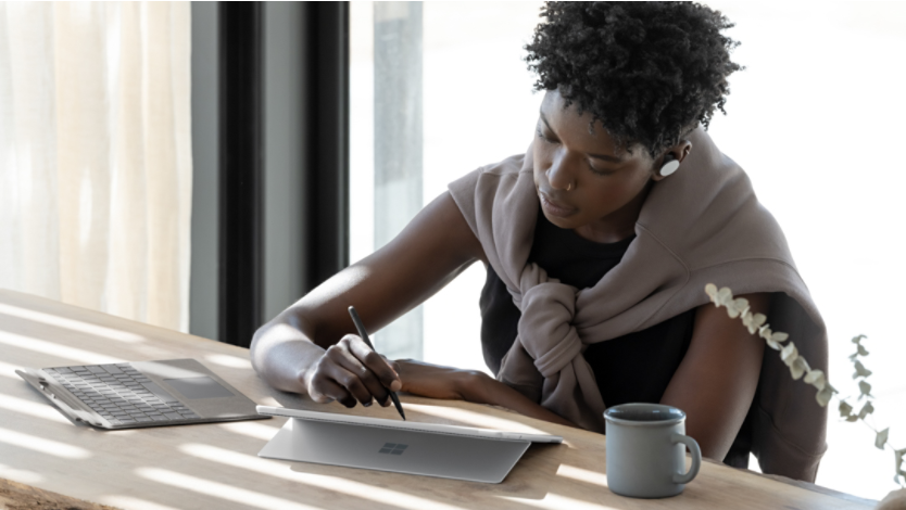 A woman sitting at a table using her Surface laptop