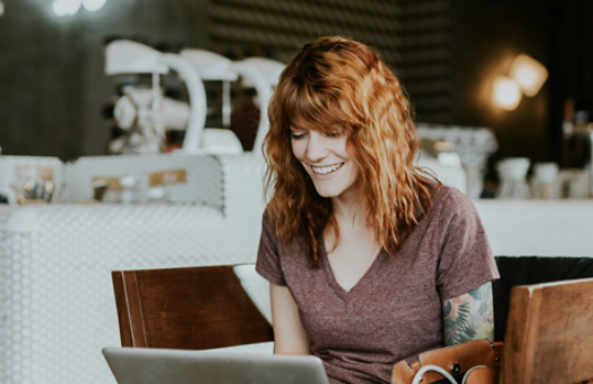 Woman sitting in a café smiling while working on her laptop