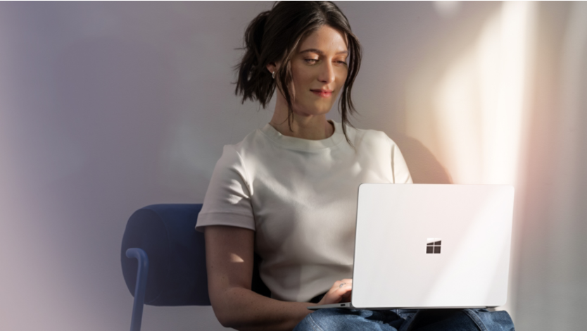 Woman sitting in a chair and using a Surface Laptop 7