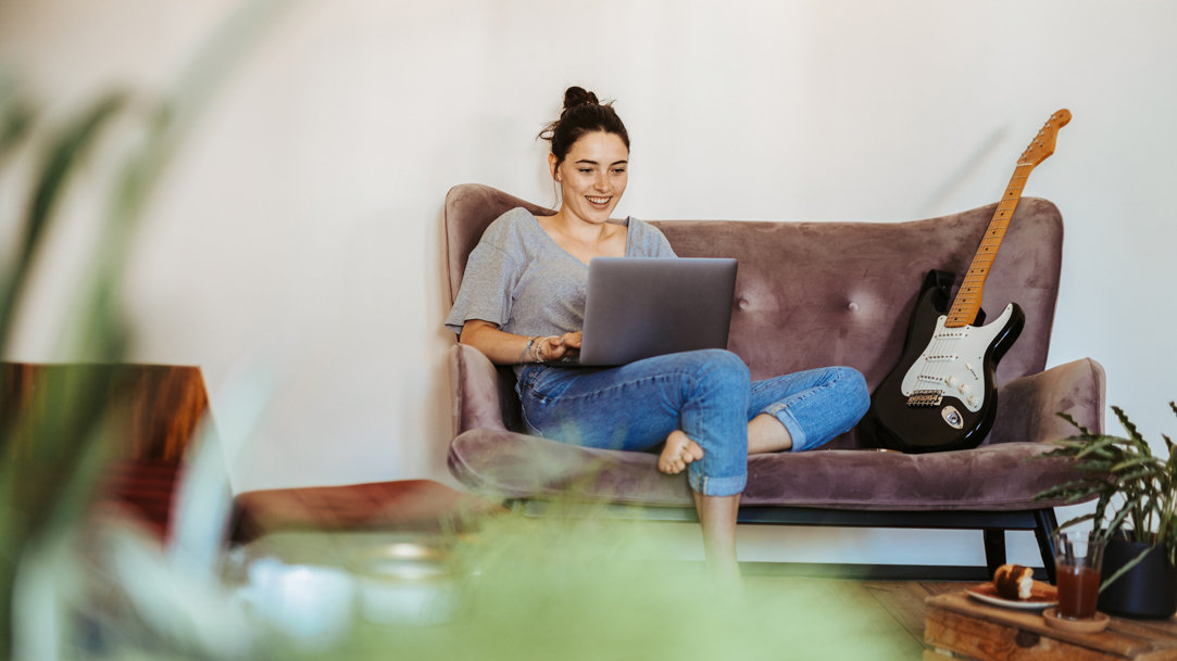 Woman sitting on a couch browsing on a laptop