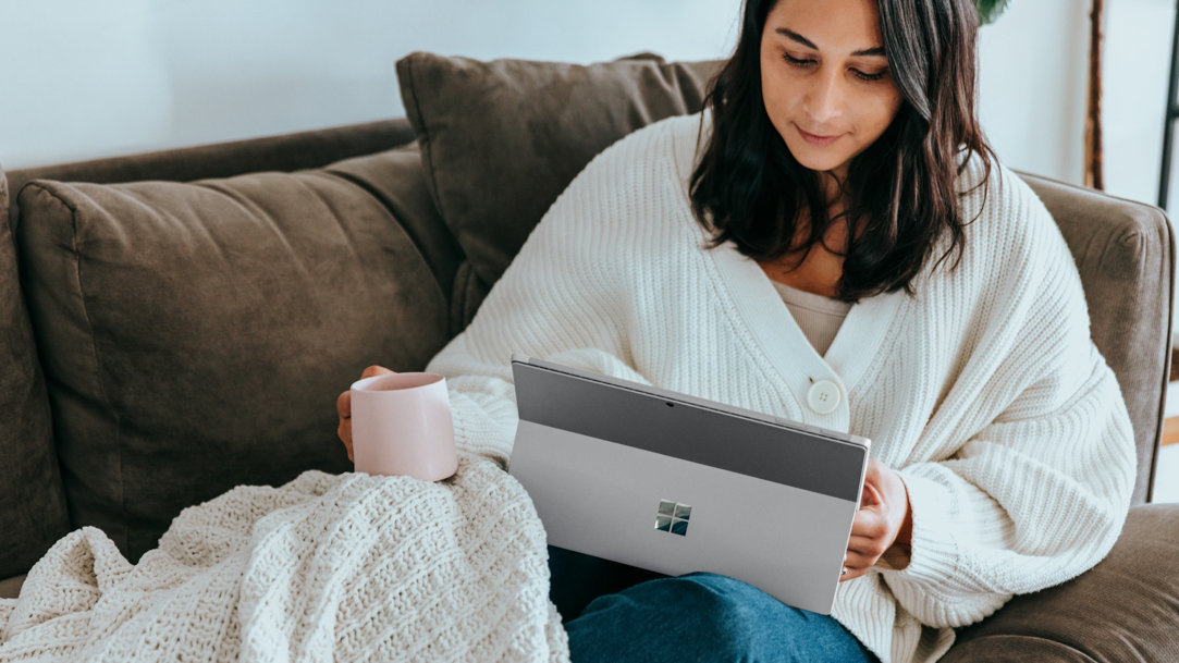 Woman sitting on the couch using a Surface device