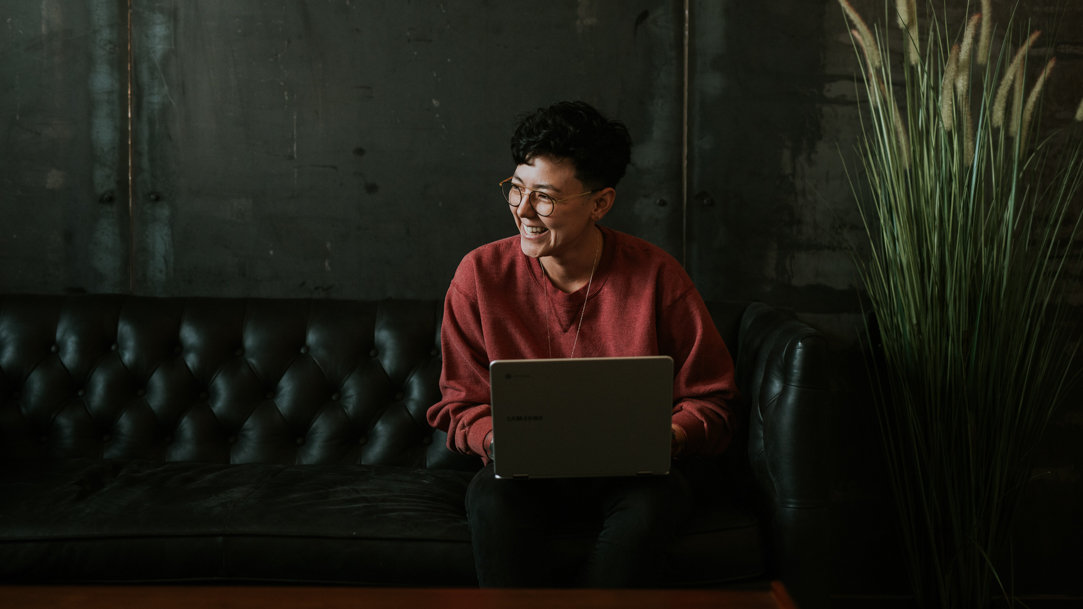 Woman smiling and working on a laptop.
