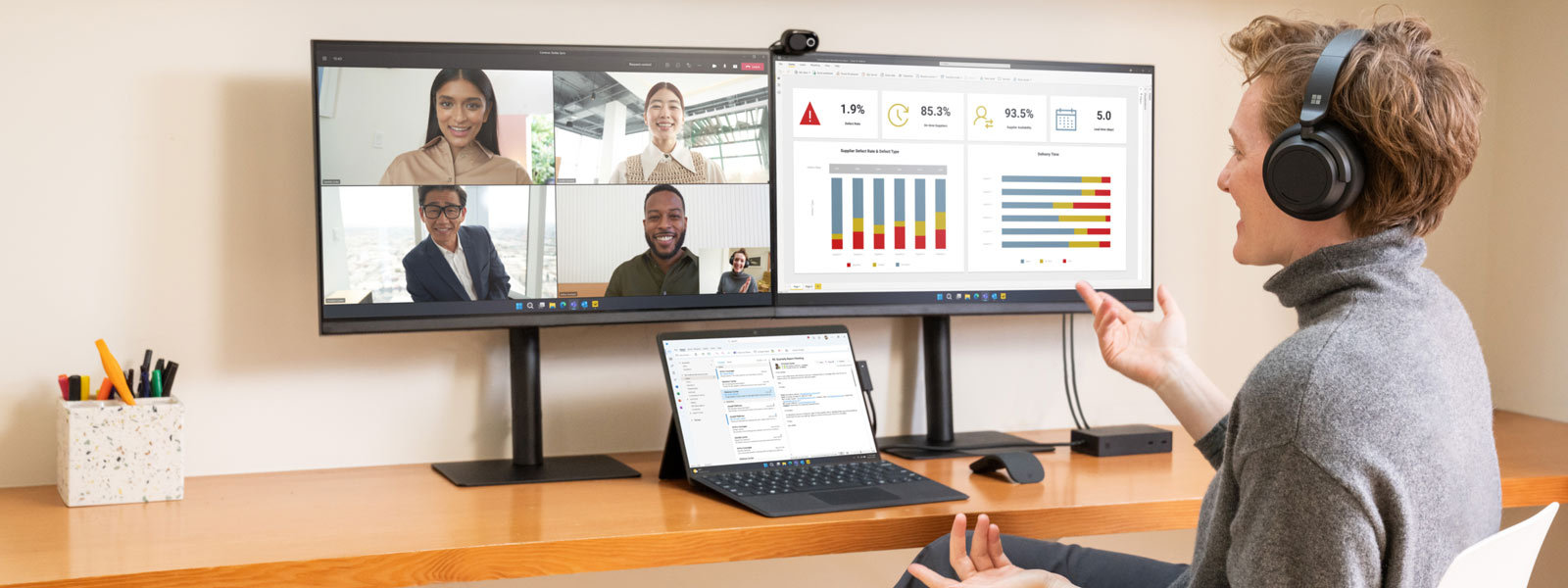 Kvinne bruker en Surface-enhet og to skjermer mens hun deltar i et virtuelt møte