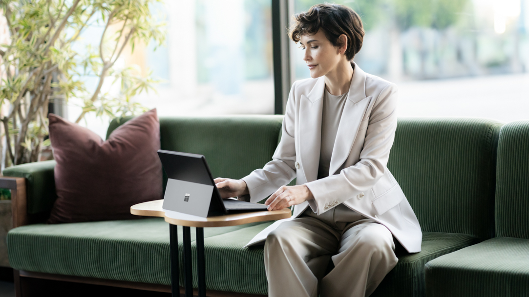 Woman using a Surface Pro 10 while sitting in a lobby chair