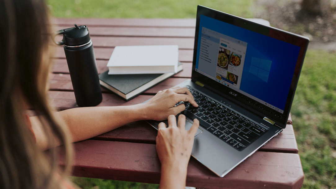 Woman using a Windows laptop outside at a picnic table