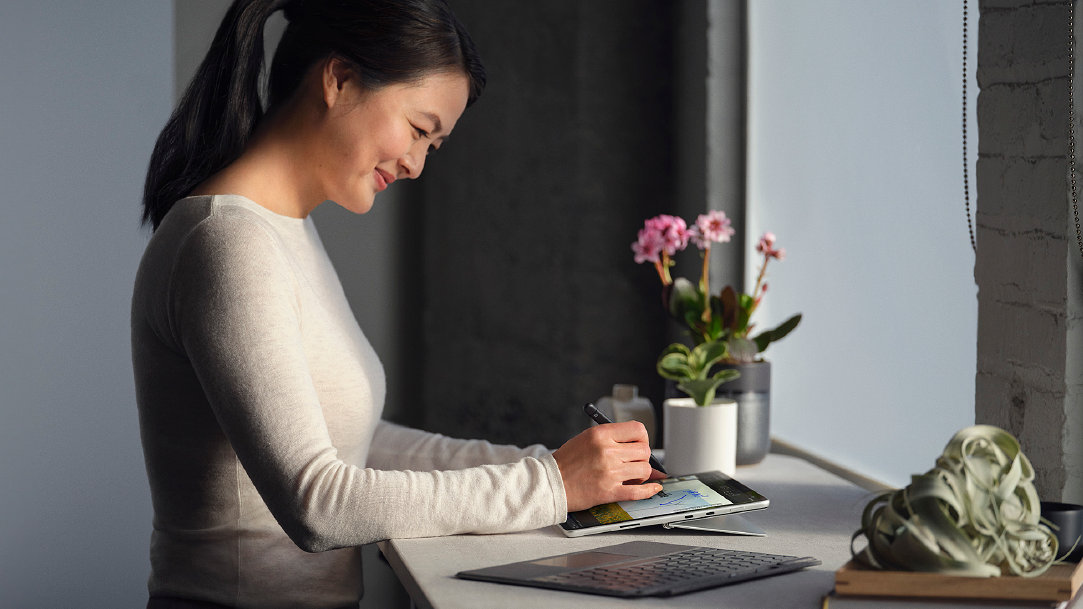 Woman using a digital pen on her Surface device on an island counter