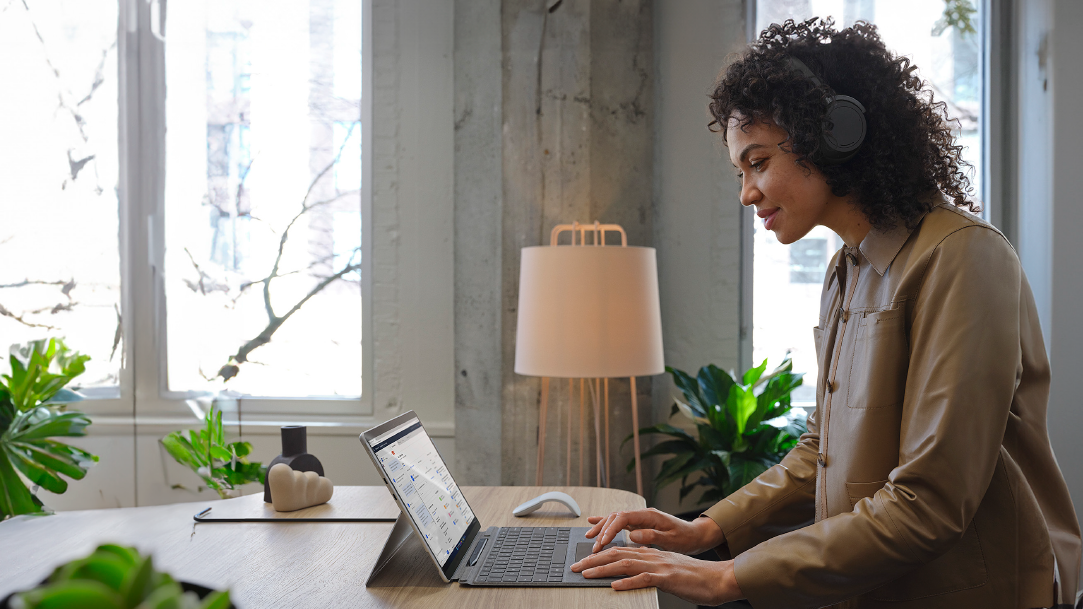 Woman wearing headphones and working on her Surface device