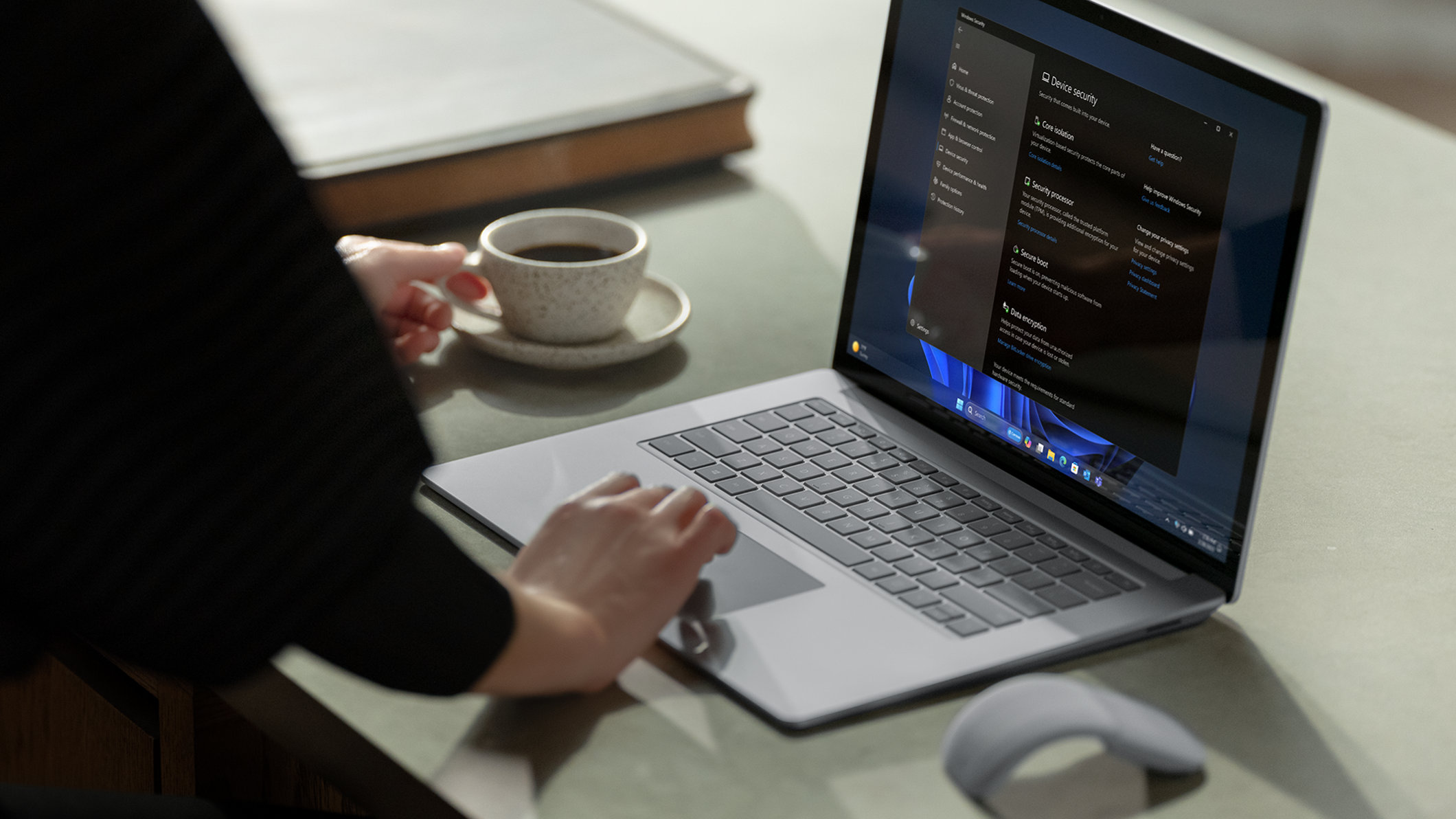 Mulher trabalhando no notebook sobre a mesa com café na outra mão