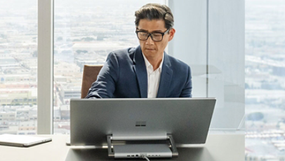 A man is using a Surface Studio 2+ in a reclined position for easier use of the touchscreen