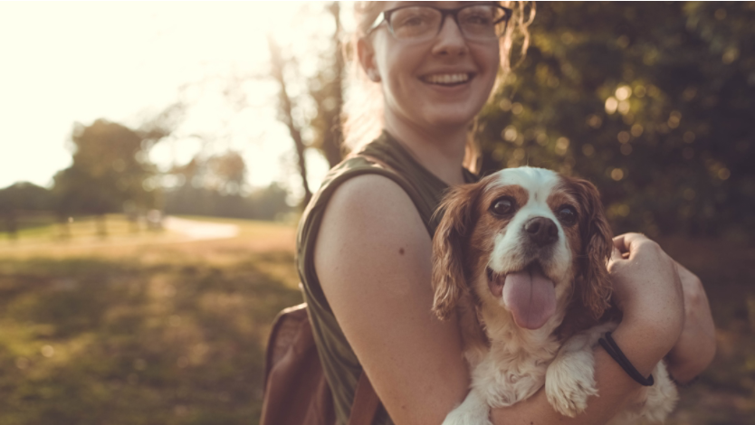 Young woman smiling with her dog outside