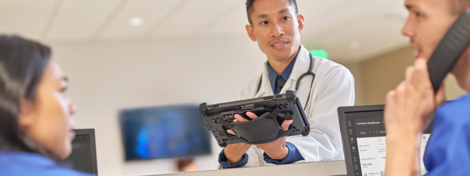 Lekarz trzymający urządzenie Surface Pro podczas rozmowy z dwiema pielęgniarkami