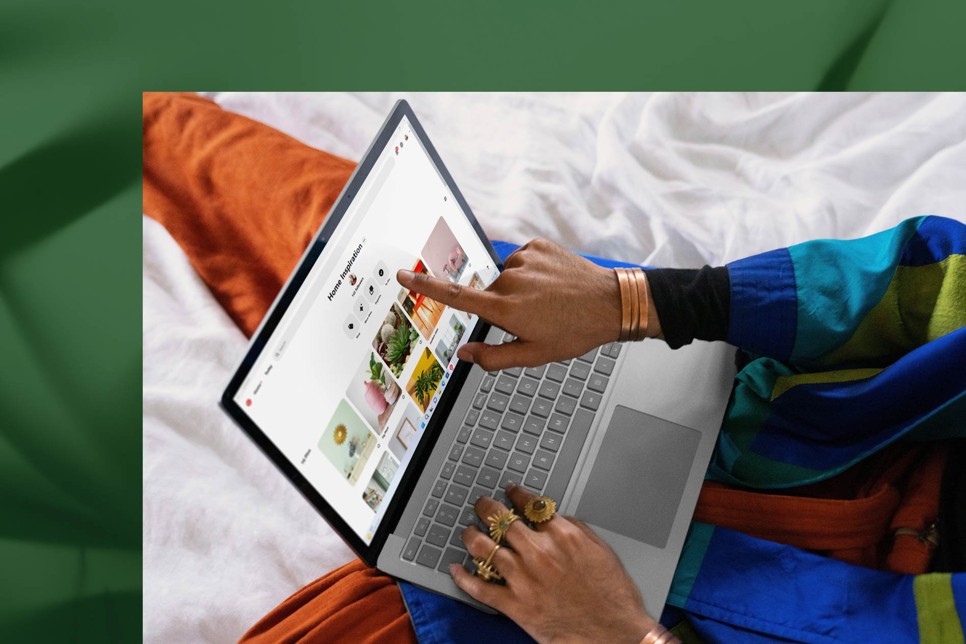 A person touches the screen of their Platinum Surface Laptop 5 while working in bed.